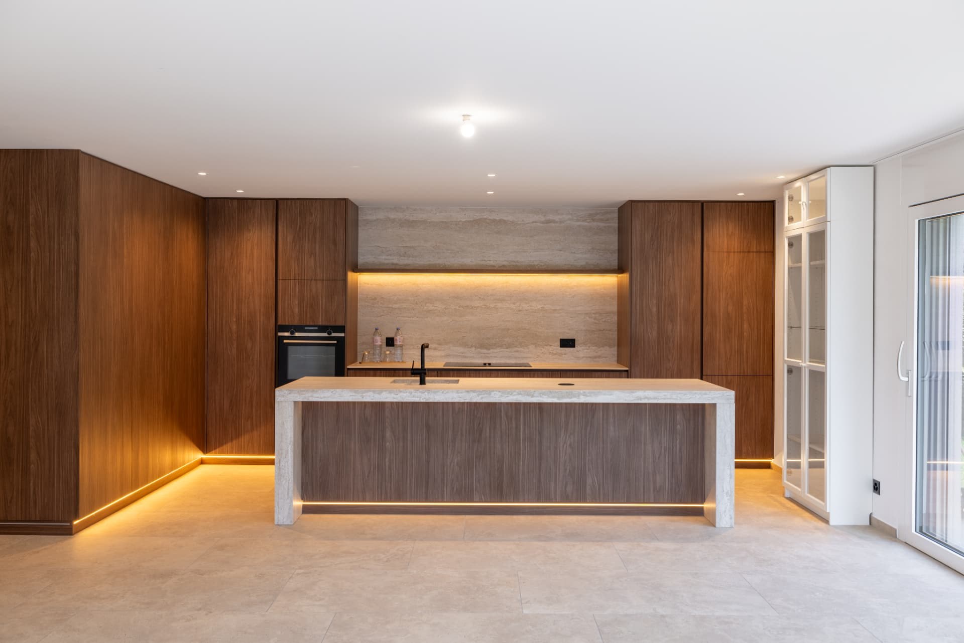 Cuisine moderne en bois foncé avec îlot central en pierre claire d'un bien immobilier en Valais